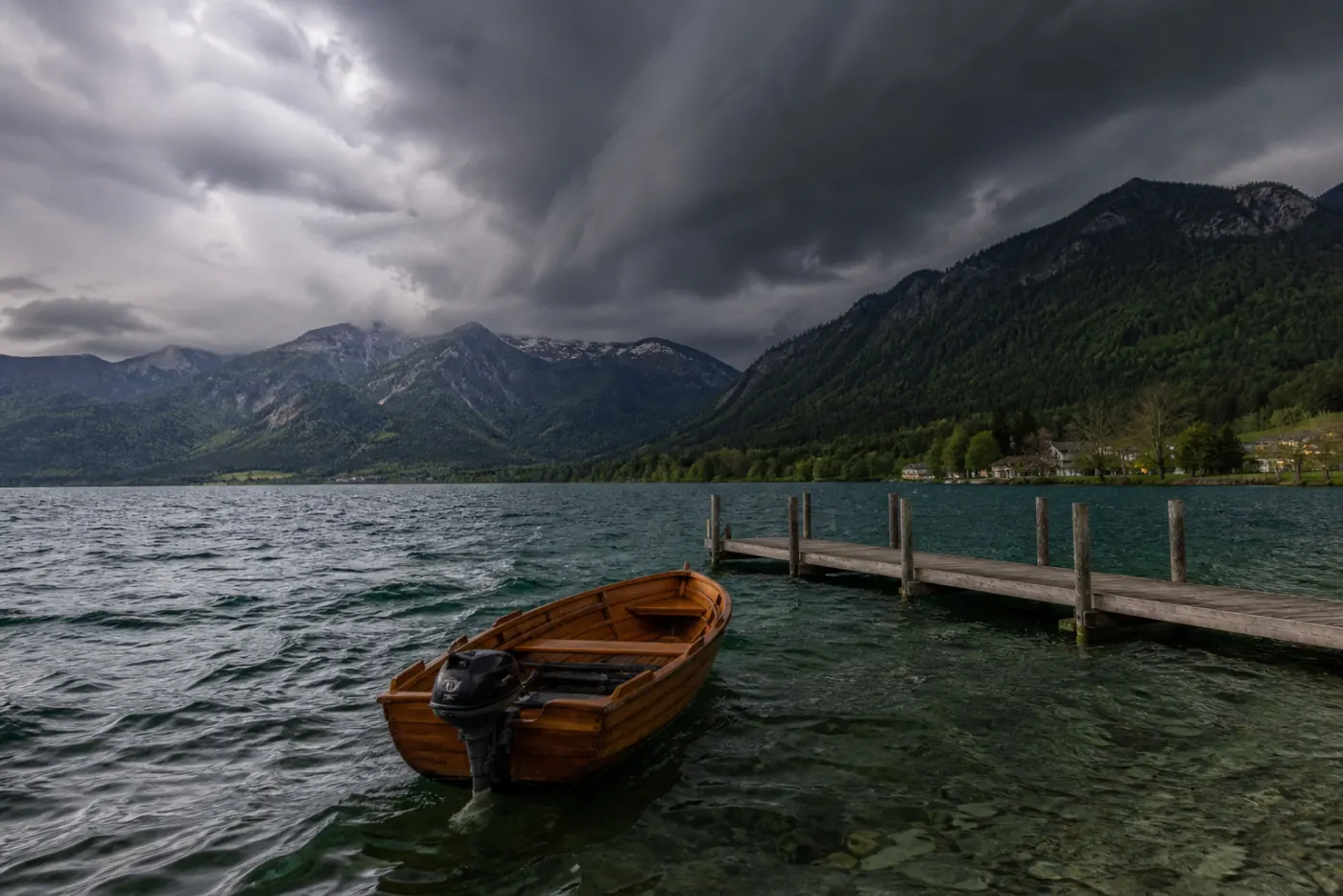 Aufziehendes Unwetter über einem Alpensee mit Angelboot am Steg nahe München